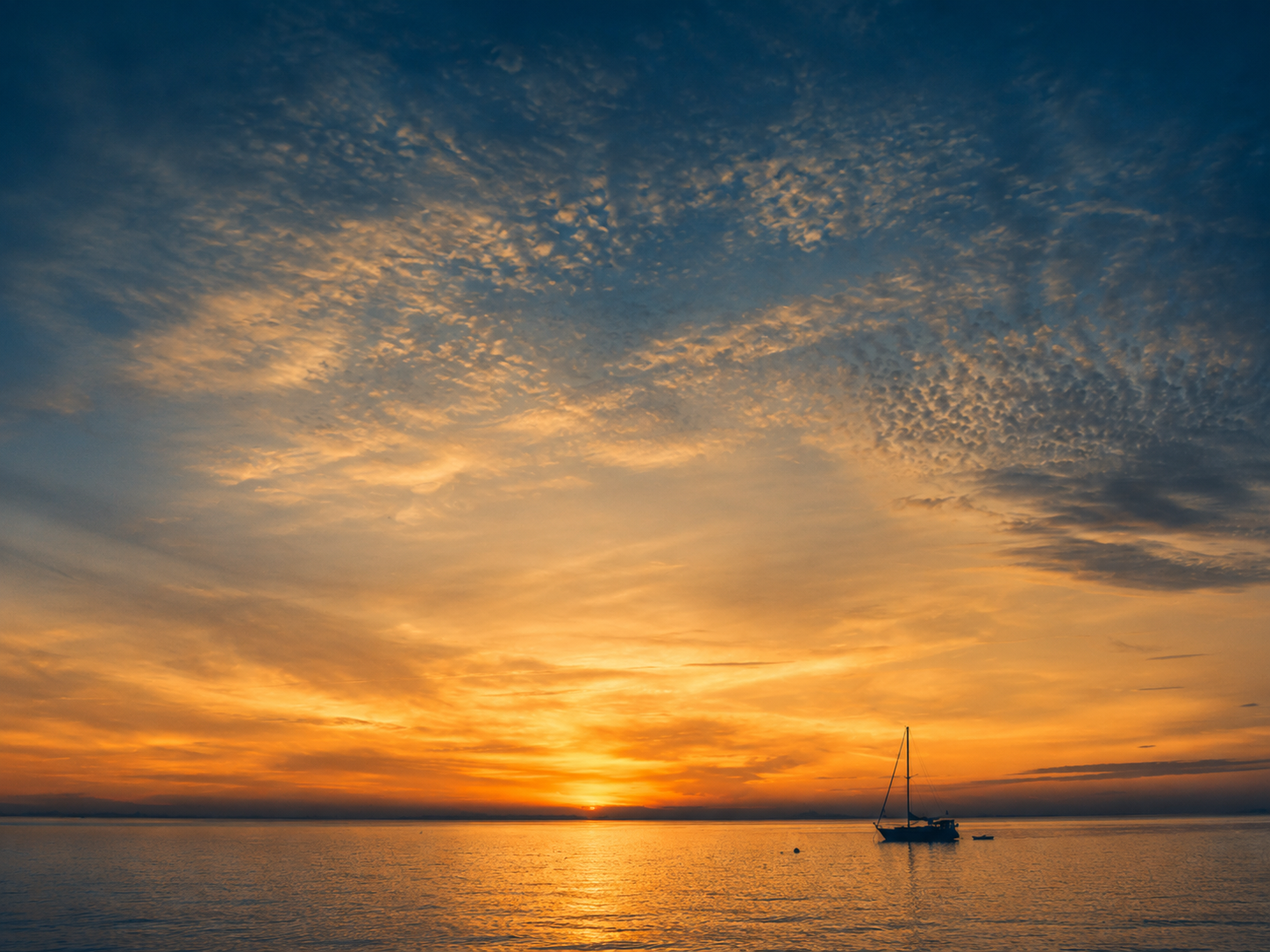 Sailboat at sunset on calm water during a private captained charter